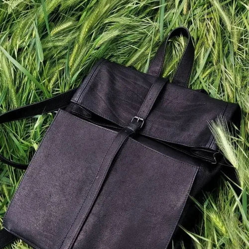 Rucsac laptop din piele nabuc negru KC Wabi-Sabi, așezat pe iarbă, vedere frontală din unghi superior