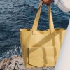 Geantă The Shopper din piele naturală galben muștar, purtată în mână la malul mării