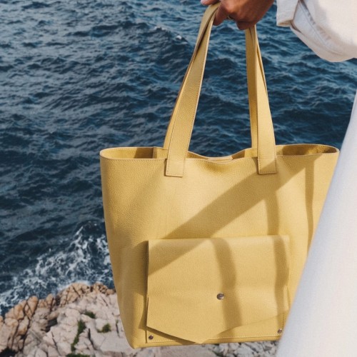Geantă The Shopper din piele naturală galben muștar, purtată în mână la malul mării