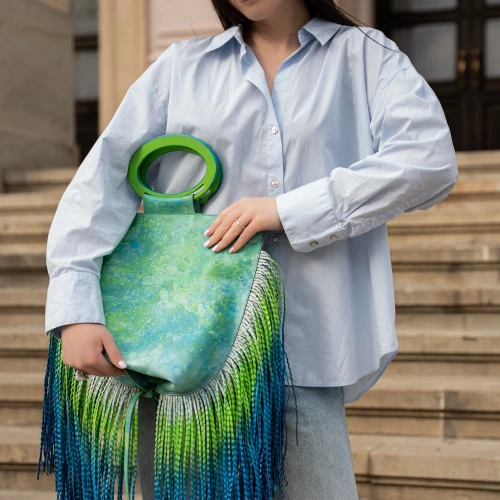 Geantă KOJA Tote Pasajero Province purtată în mână, cu mâner circular verde și finisaj pictat în tonuri verde-albastru.
