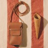 Husă de telefon Smart din piele naturală maro, cu șnur lung, pe fundal textil în dungi